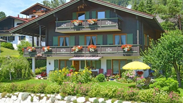 Un chalet traditionnel doté d’un balcon, d’un jardin fleuri et surplombant les montagnes.