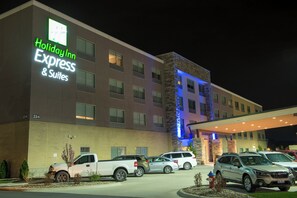 A Holiday Inn Express & Suites building with a brick facade, multiple windows, and a parking lot with several vehicles. - Holiday Inn Express & Suites Orland Park - Mokena by IHG (Mokena)