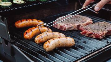 A grill with sausages and meat being cooked.