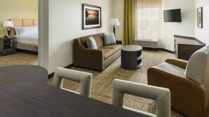 A hotel room with a bed, a sofa, a dining table, and a TV. - Candlewood Suites Orlando - Lake Buena Vista by IHG (Orlando)