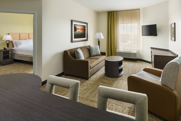 A hotel room with a bed, a sofa, a dining table, and a TV. - Candlewood Suites Orlando - Lake Buena Vista by IHG (Orlando)
