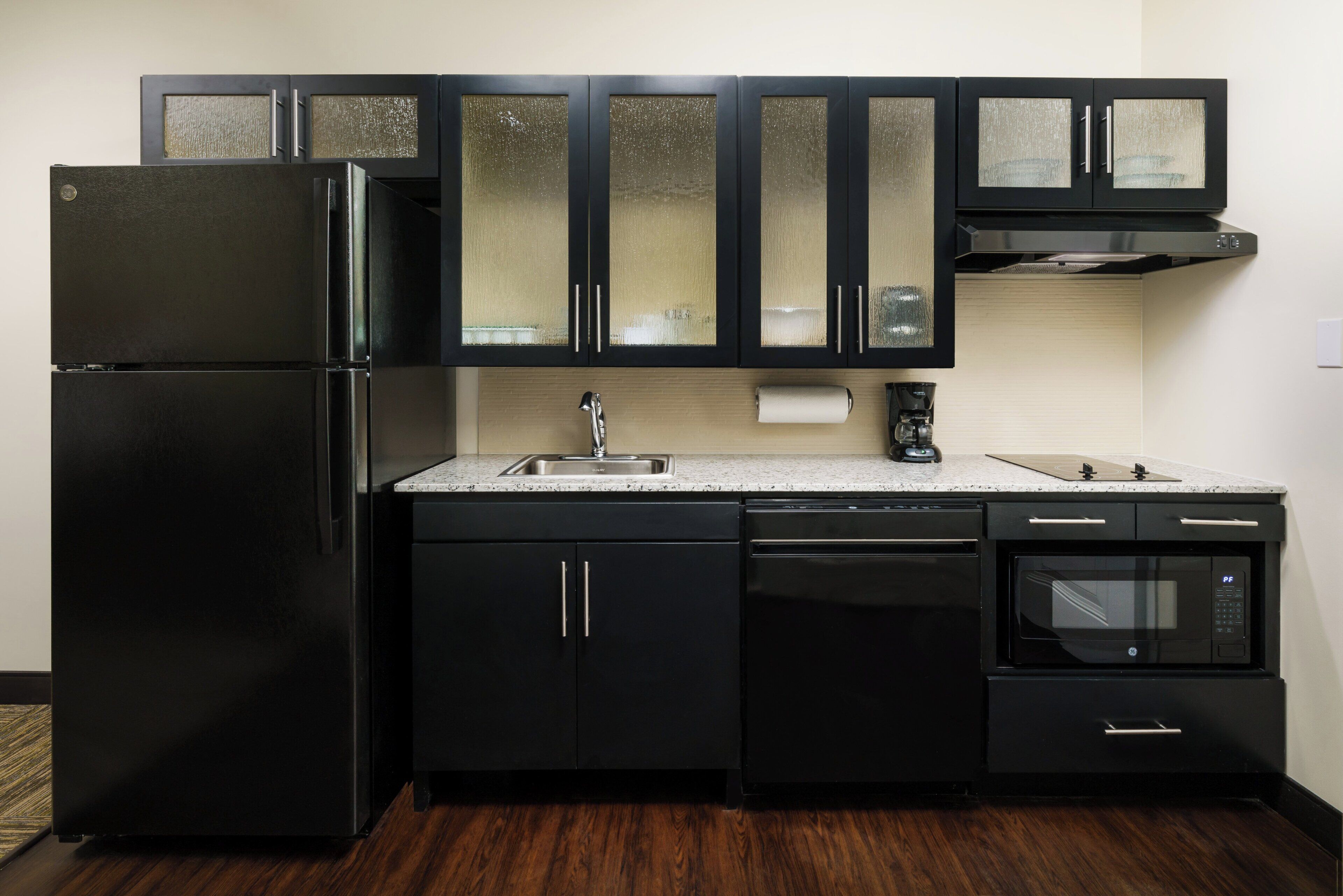 A kitchen with black appliances, a stainless steel sink, and a built-in oven.