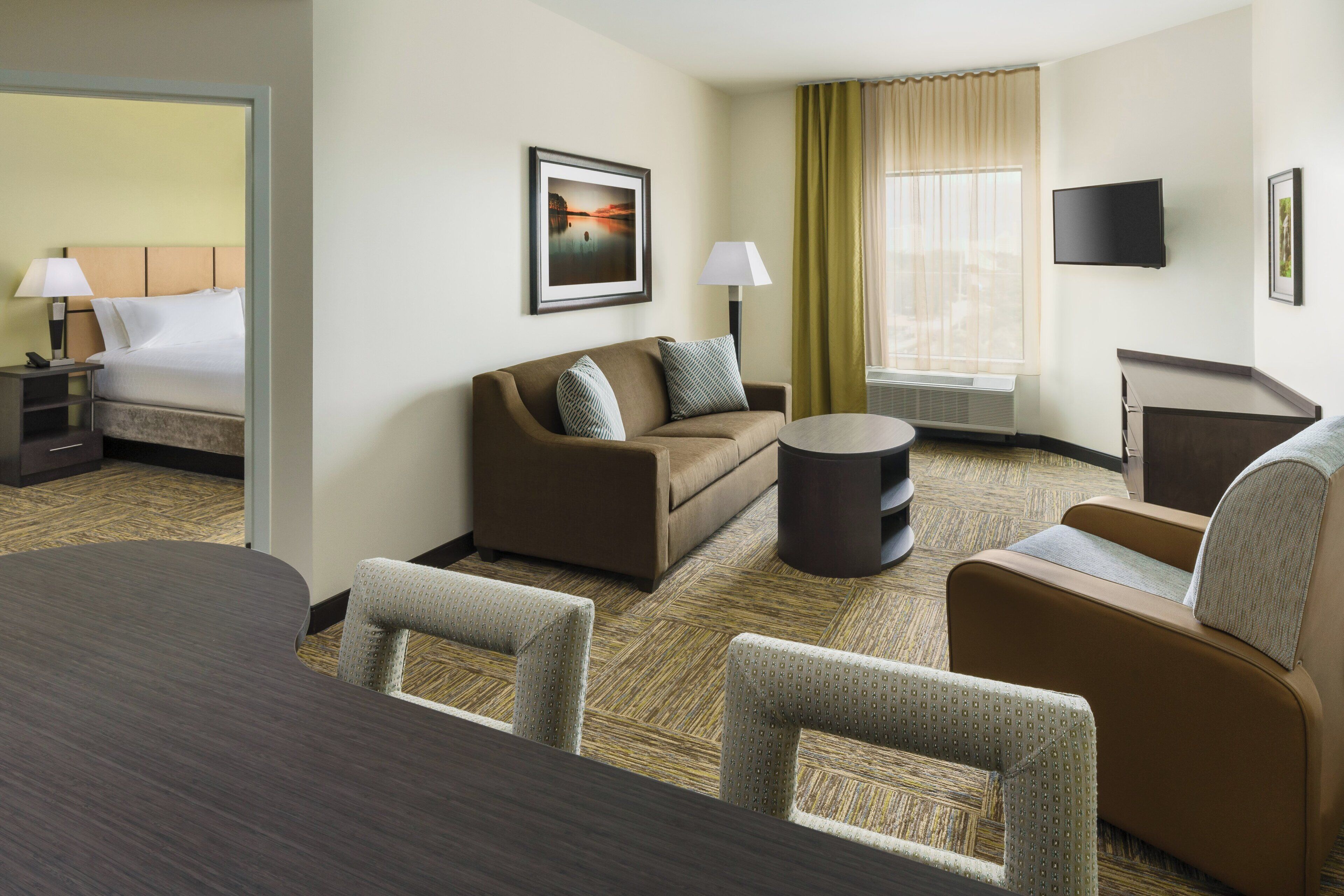 Una habitación de hotel con cama, sofá, mesa de centro y televisión.