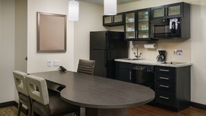 A modern kitchen with a black refrigerator, a microwave, and a coffee maker. There is a dining table with chairs and a bulletin board on the wall. - Candlewood Suites Orlando - Lake Buena Vista by IHG (Orlando)