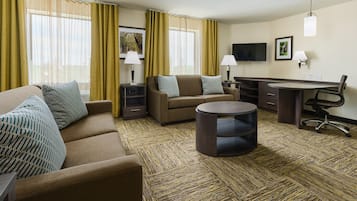 Ein Hotelzimmer mit einer Couch, einem runden Couchtisch, einem Schreibtisch und einem Stuhl.