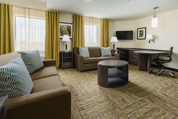 Una habitación de hotel con sofá, una mesita redonda, escritorio y una silla.