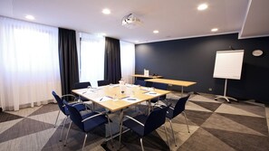 A conference room with a large table, chairs, a projector, and a whiteboard.
