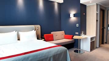 A hotel room with a bed, a desk, and a seating area.