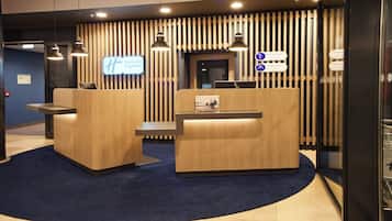 A reception area with two wooden reception desks, a digital display, and a sign indicating a general manager and duty employee.