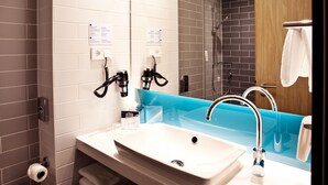 Un baño moderno con un lavamanos blanco, encimera azul y ducha con mampara de vidrio.