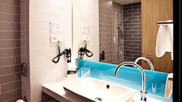 Un baño moderno con un lavamanos blanco, un espejo y una zona de ducha.