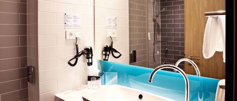 Un baño moderno con un lavamanos blanco, un espejo y una zona de ducha.