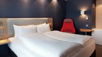 Una habitación de hotel con una cama, una silla roja y una mesita de noche.