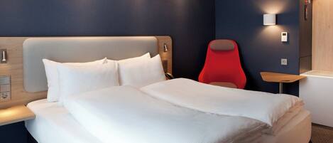 Una habitación de hotel con una cama, una silla roja y una mesita de noche.