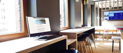 A modern hotel room with a desk, computer, and seating area.