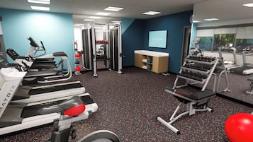 A gym with treadmills, weight machines, and a mirrored wall.