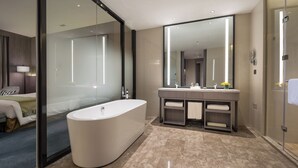 A modern bathroom with a freestanding bathtub, a large mirror, and a vanity with multiple sinks and towel racks. - Holiday Inn Xining Hot-Spring by IHG (Xining)