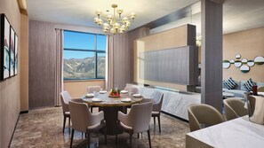 A modern dining area with a round table, chairs, and a view of the mountains through large windows.