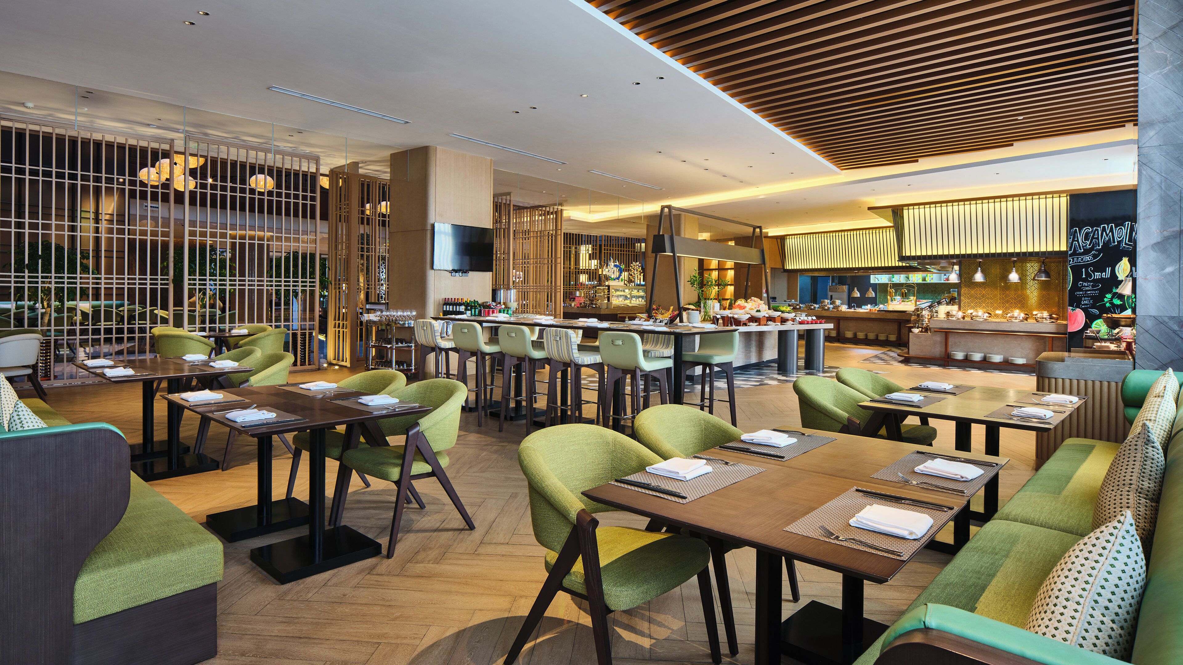 Un interior de restaurante moderno con varias zonas de comedor, bar y cocina a la vista.