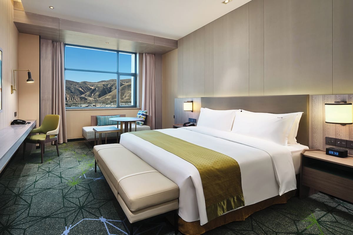 Ein Hotelzimmer mit Bett, Schreibtisch, Stuhl, einem kleinen Tisch und Bergblick durch das Fenster.
