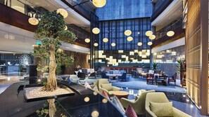 A spacious lobby with a central tree, seating areas, and a modern reception desk. - Holiday Inn Xining Hot-Spring by IHG (Xining)