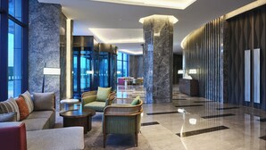 A modern lobby with seating, a reception desk, and a large pillar.