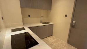 A compact kitchen with a built-in stove, a sink, and grey cabinets. - Holiday Inn Xining Hot-Spring by IHG (Xining)