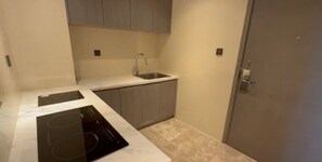 A compact kitchen with a built-in stove, a sink, and grey cabinets. - Holiday Inn Xining Hot-Spring by IHG (Xining)