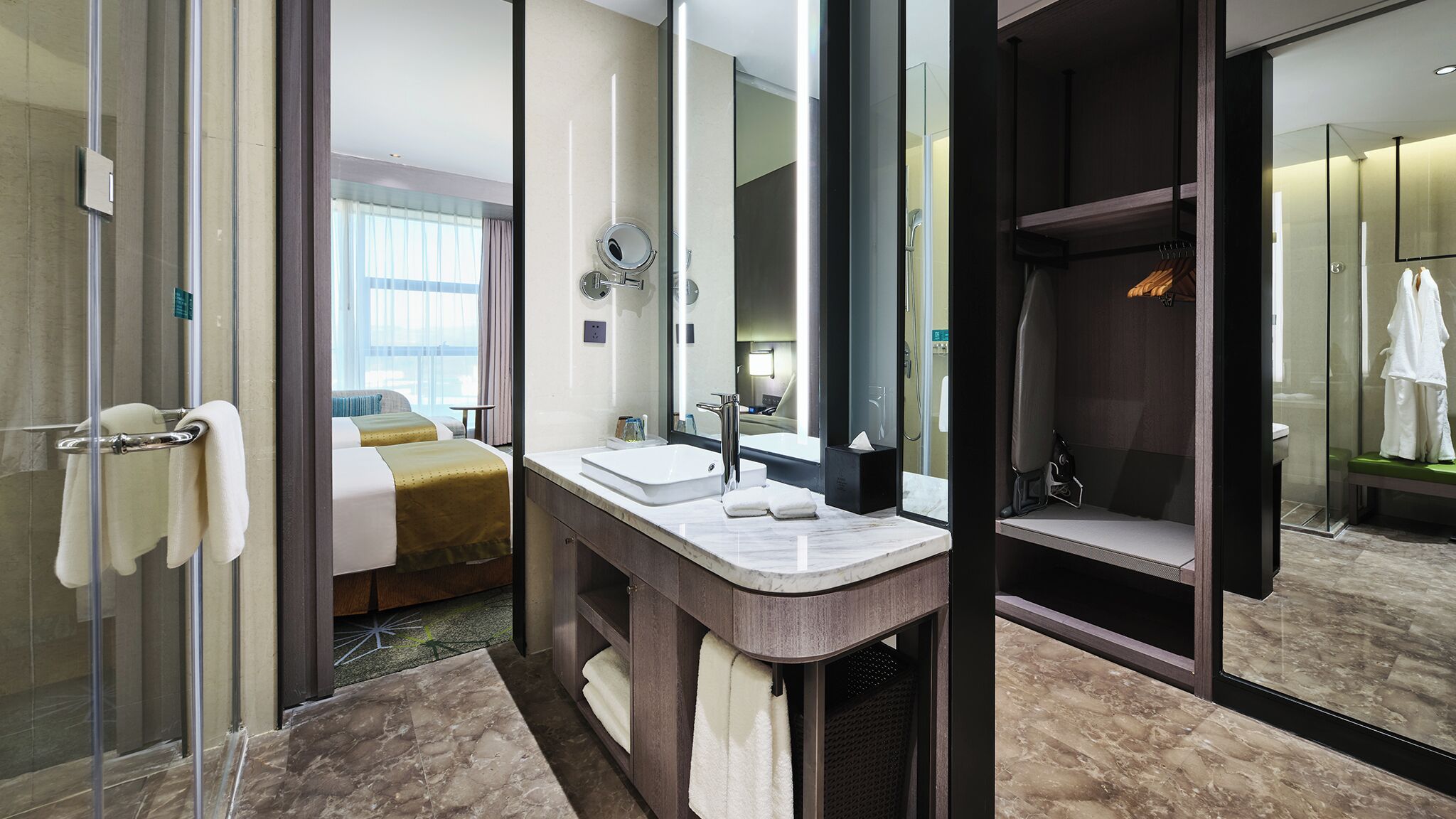 Habitación de hotel con una cama grande, un baño con lavamanos doble y un vestidor.