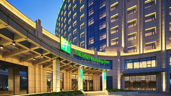 A hotel entrance with a modern design, featuring a prominent sign and a covered walkway.