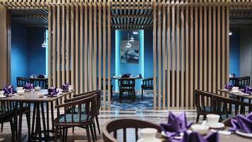 A restaurant with multiple tables and chairs, a blue wall, and a framed artwork on the wall.