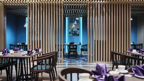 A restaurant with multiple tables and chairs, a blue wall, and a framed artwork on the wall. - Holiday Inn Xining Hot-Spring by IHG (Xining)