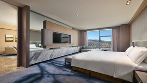 A modern hotel room with a large bed, a TV mounted on the wall, and a view of the mountains. - Holiday Inn Xining Hot-Spring by IHG (Xining)