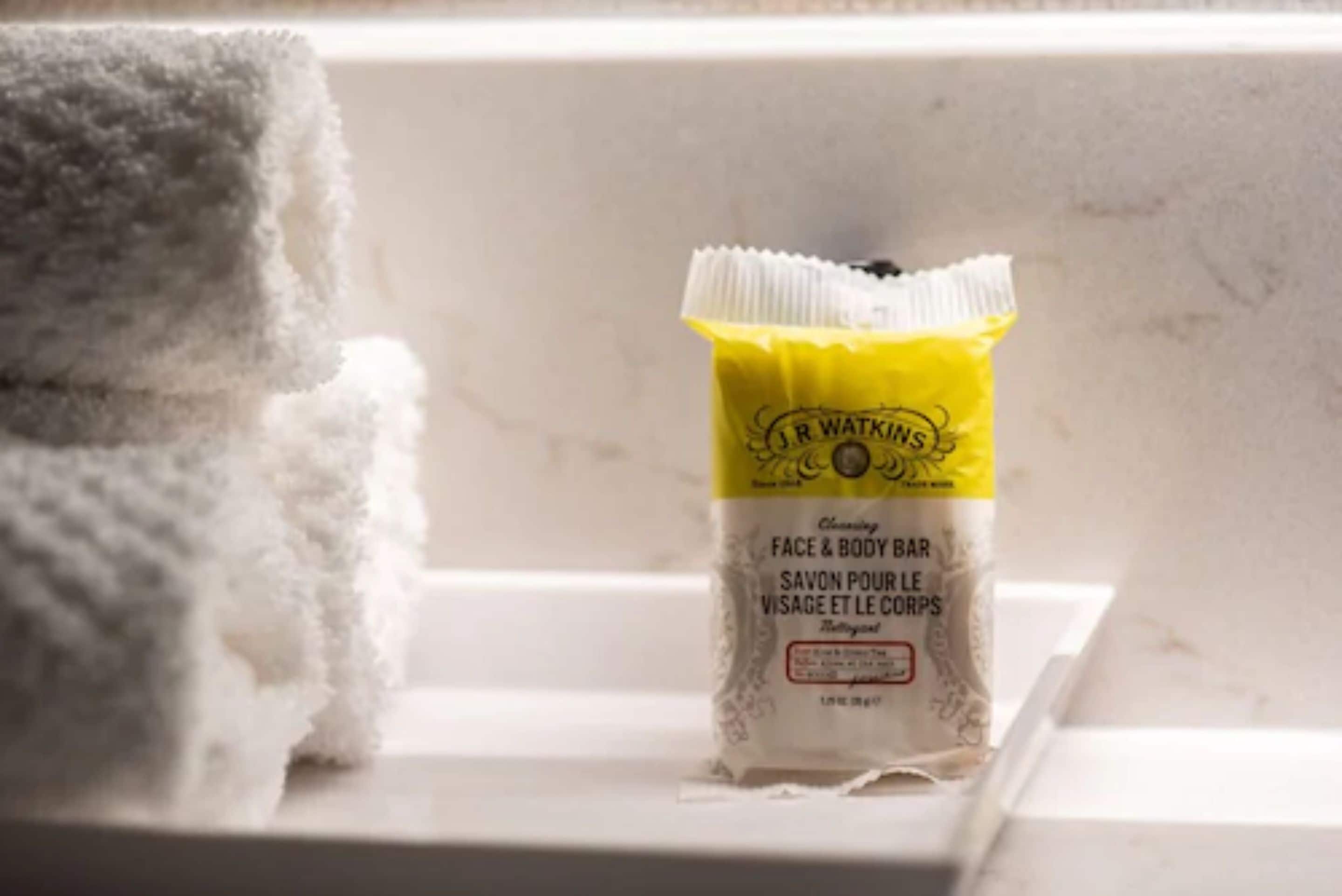 Un baño con una toalla y una barra de jabón sobre un lavabo blanco.