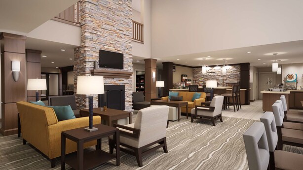 A spacious lobby with a stone fireplace, comfortable seating, and a bar area. - Staybridge Suites Waterloo - St. Jacobs Area by IHG (Township of Woolwich)