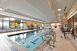 An indoor swimming pool with clear lane markings, a lifeguard chair, and a view of the outdoors through large windows. - Staybridge Suites Waterloo - St. Jacobs Area by IHG (Township of Woolwich)