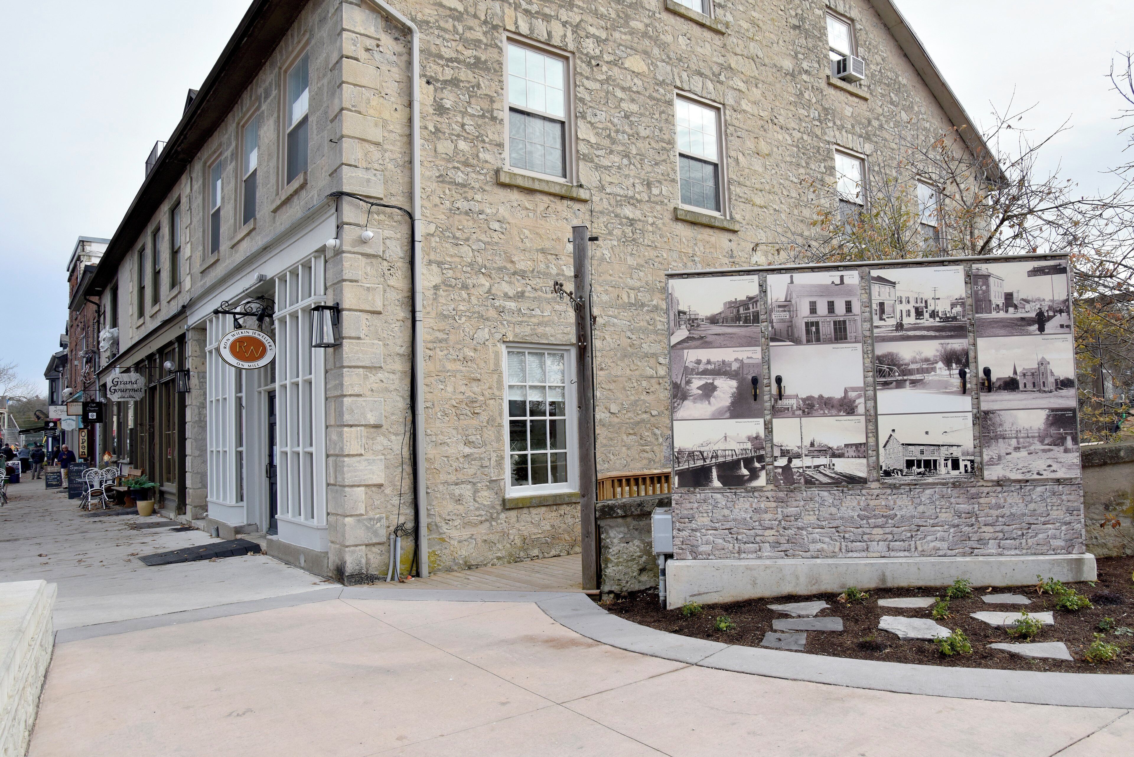 Un bâtiment en pierre avec un magasin au rez-de-chaussée et une exposition historique sur le trottoir.