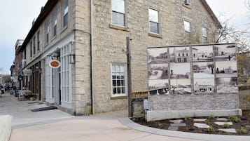 Un bâtiment en pierre avec un magasin au rez-de-chaussée et une exposition historique sur le trottoir.