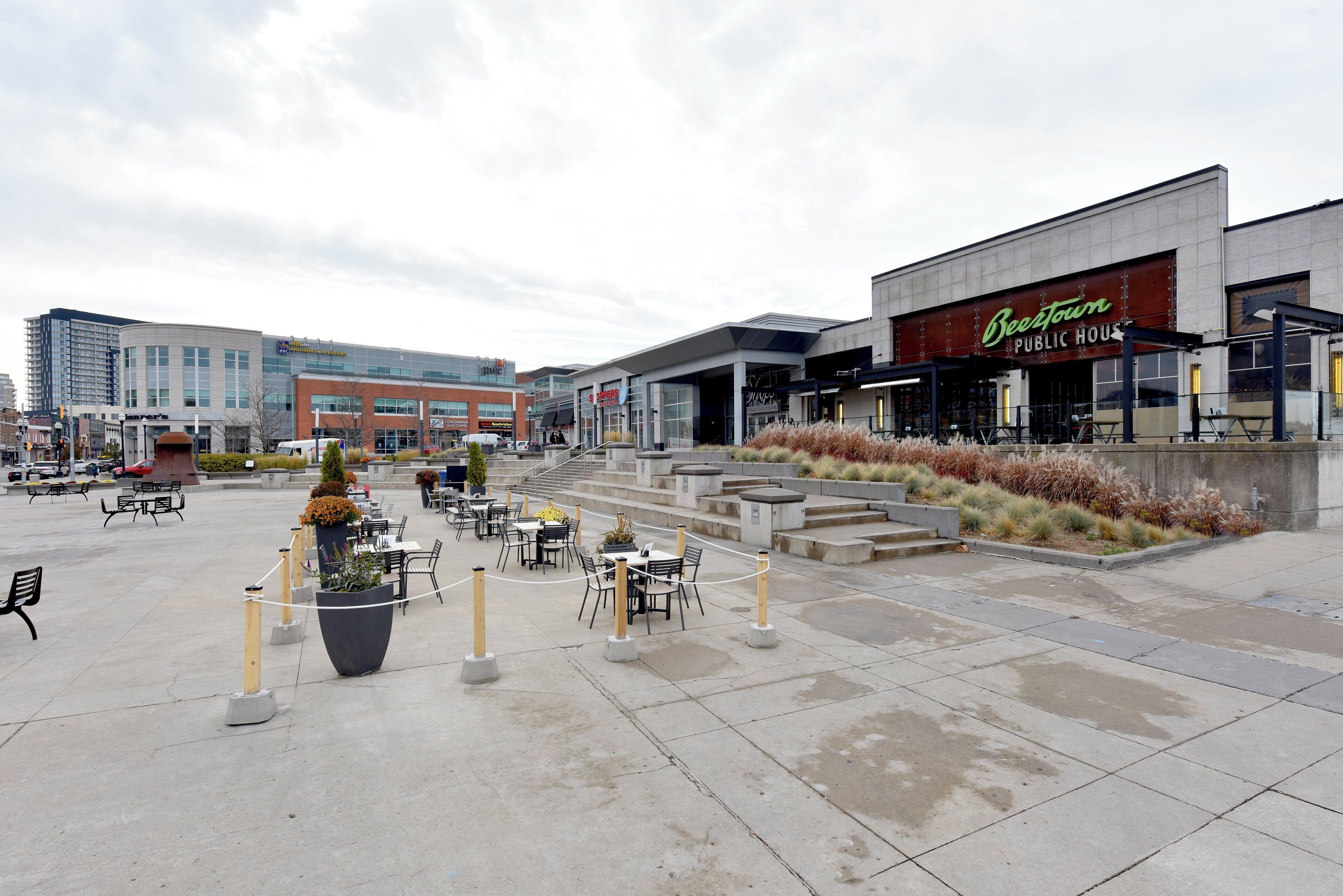 An outdoor seating area with tables and chairs, surrounded by a low fence.