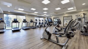 Une salle de sport équipée de tapis de course, de vélos elliptiques et de matériel de musculation.