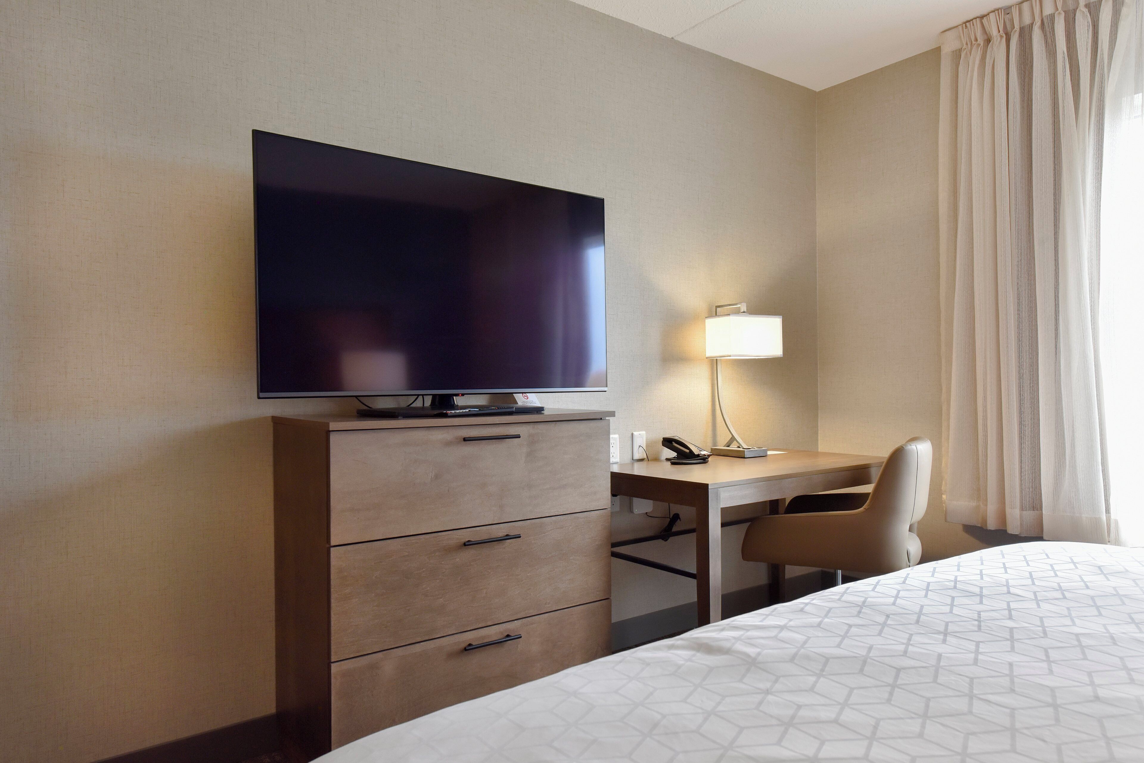 Une chambre d’hôtel comprenant un lit, un bureau, une chaise, une télévision et une lampe.