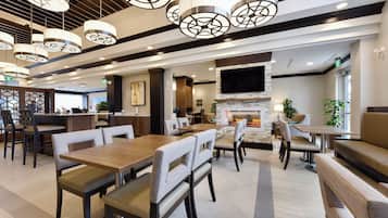 Een modern restaurantinterieur met hoge plafonds, hanglampen, een bar en een open haard.