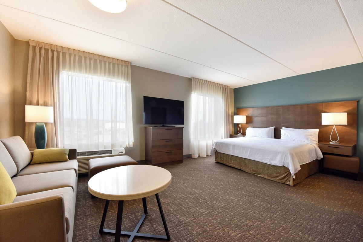 A hotel room with a bed, a TV, a desk, and a chair.