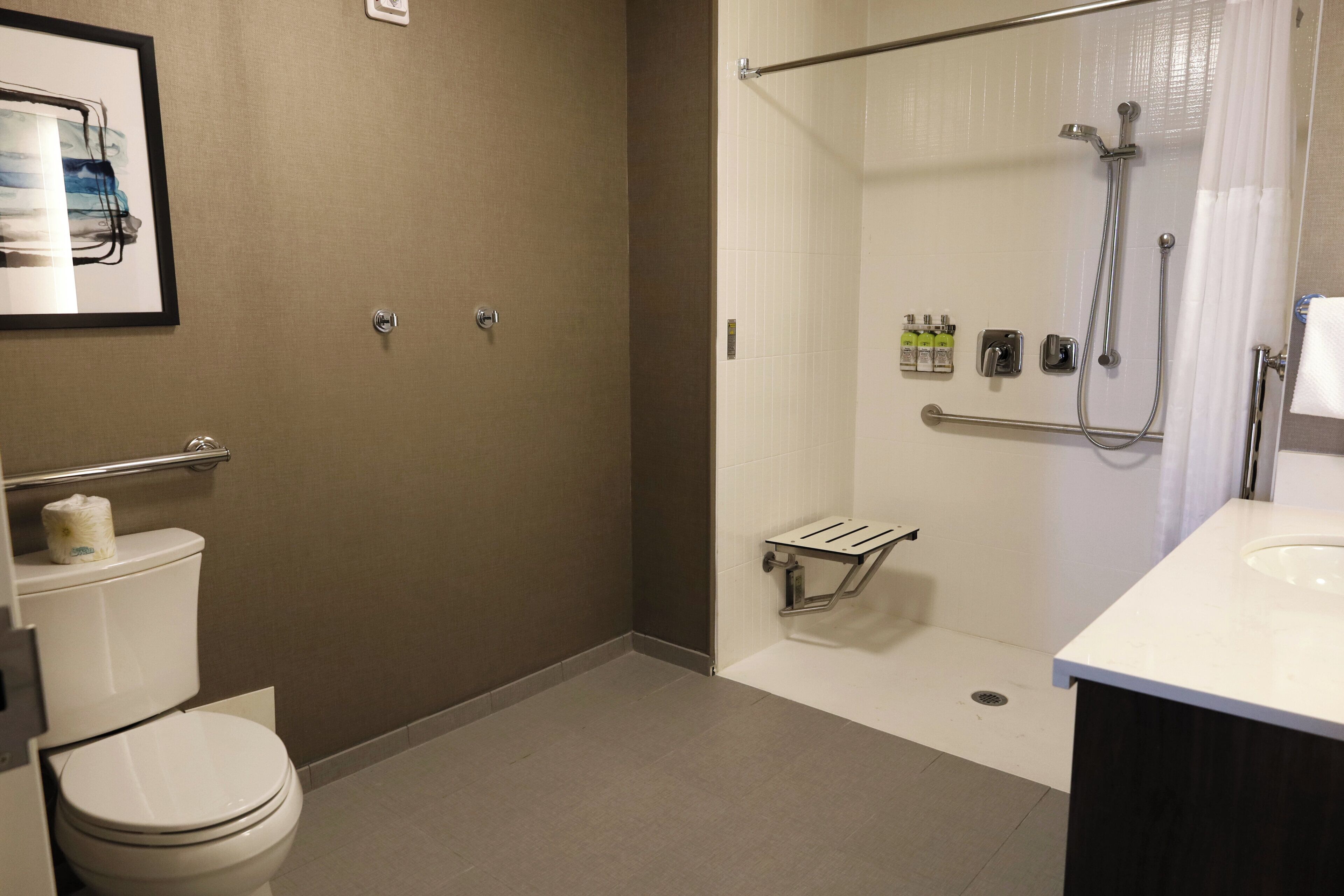 A bathroom with a toilet, a shower area, and a sink.