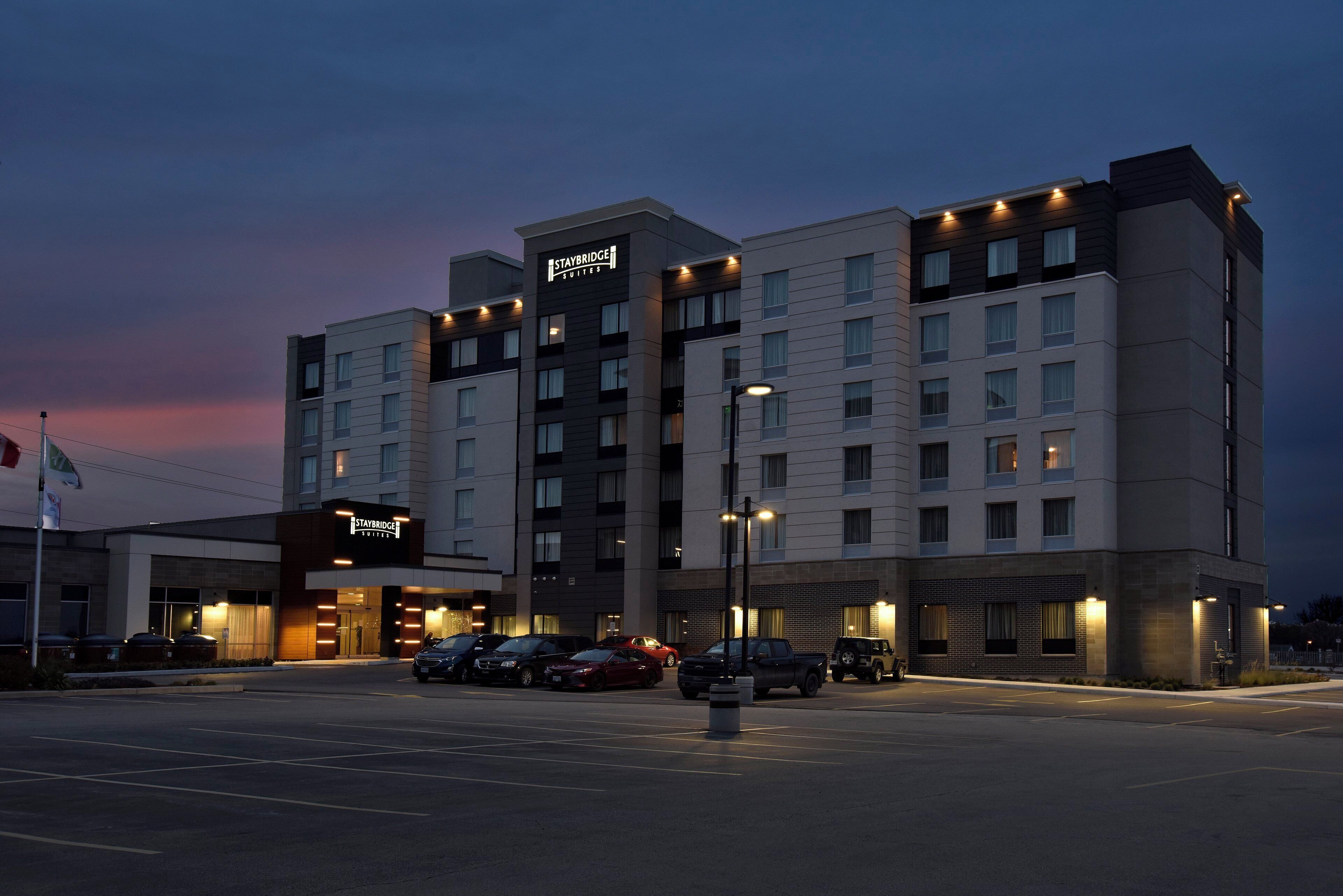 A Staybridge Suites hotel with multiple floors, a parking lot, and a clear sky.
