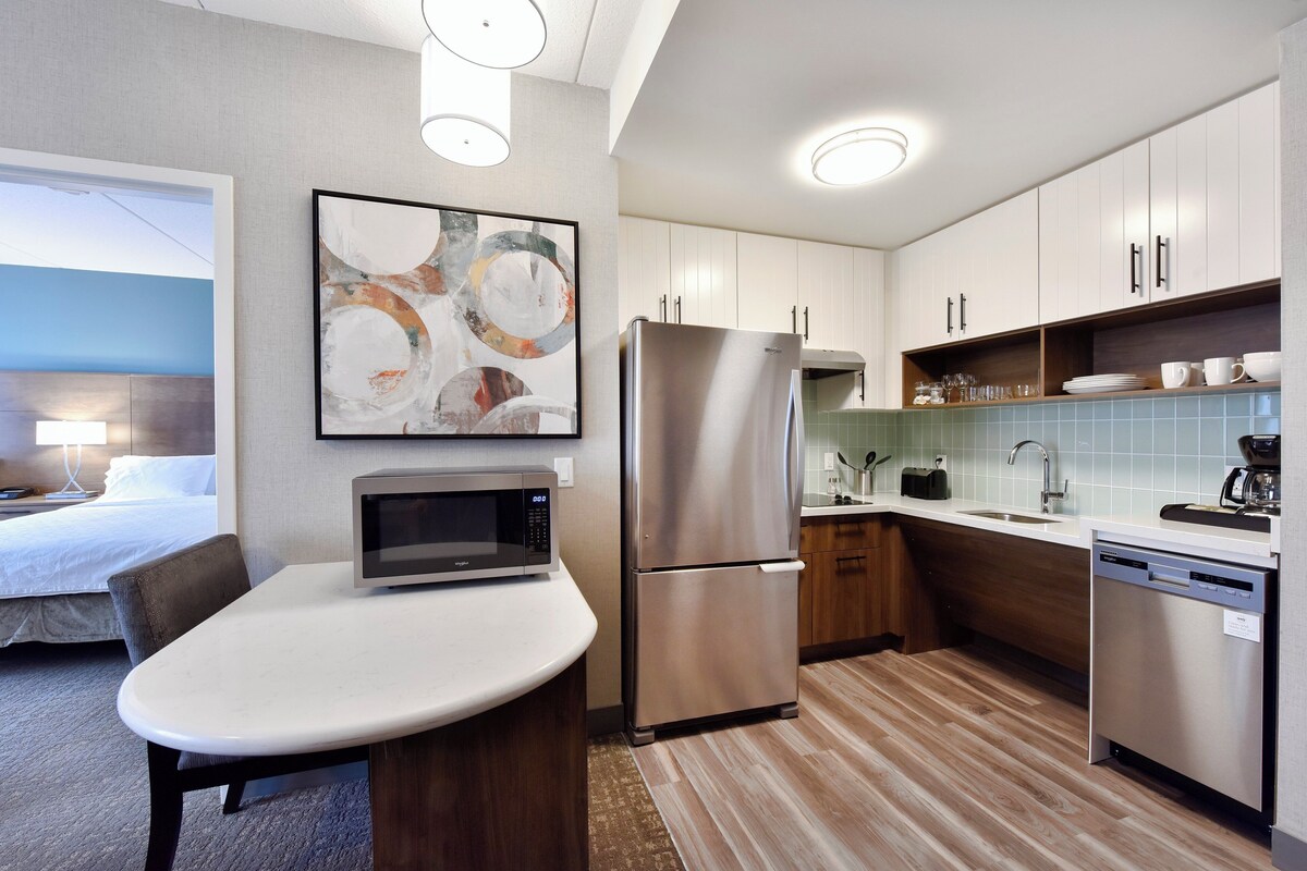 A modern kitchen with a microwave, refrigerator, and a dining area with a table and chairs.