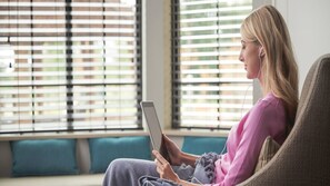 A person sitting on a couch in a room with large windows and a view of buildings outside. - Staybridge Suites Waterloo - St. Jacobs Area by IHG (Township of Woolwich)