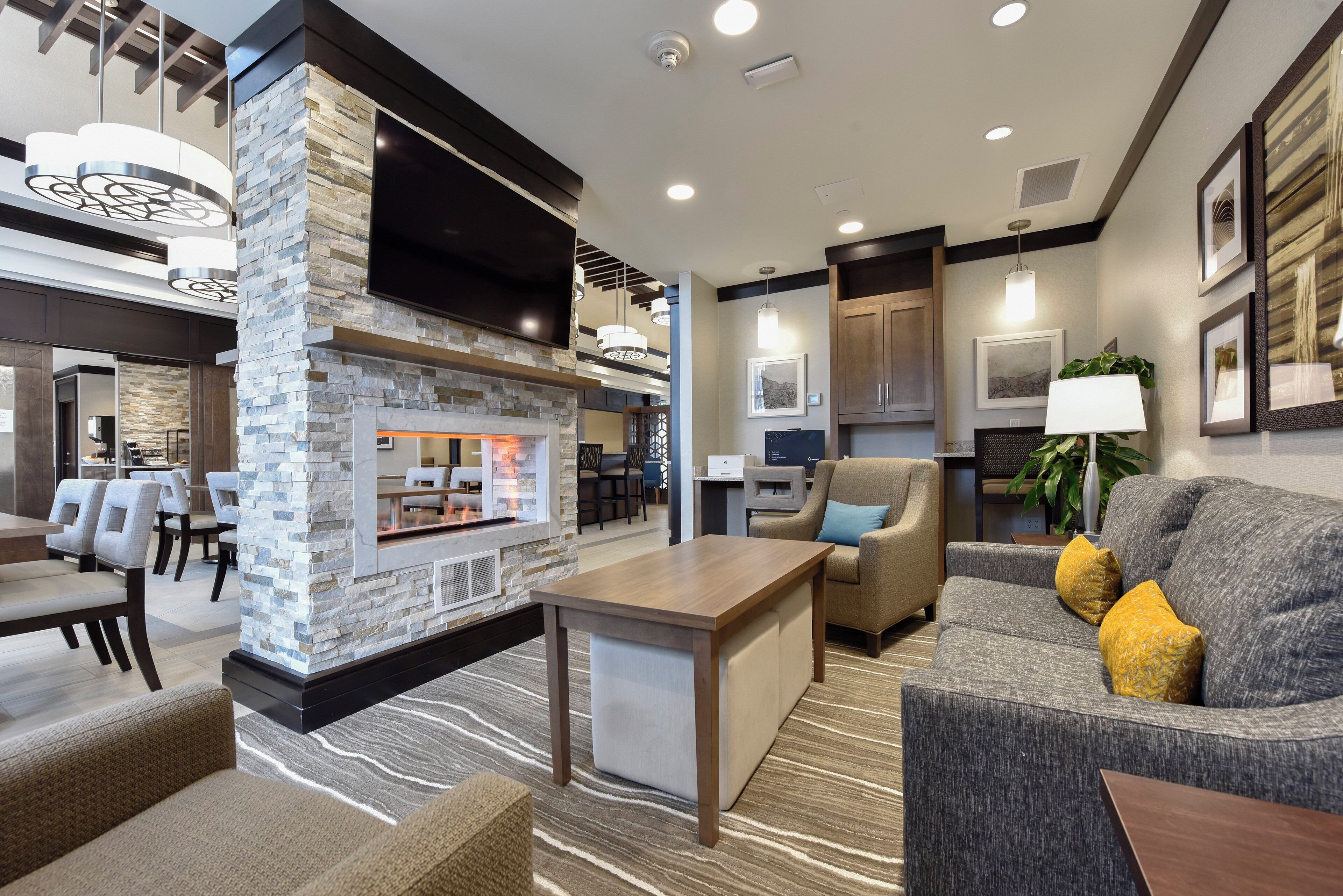 A modern living area with a stone fireplace, seating, and a flat-screen TV.