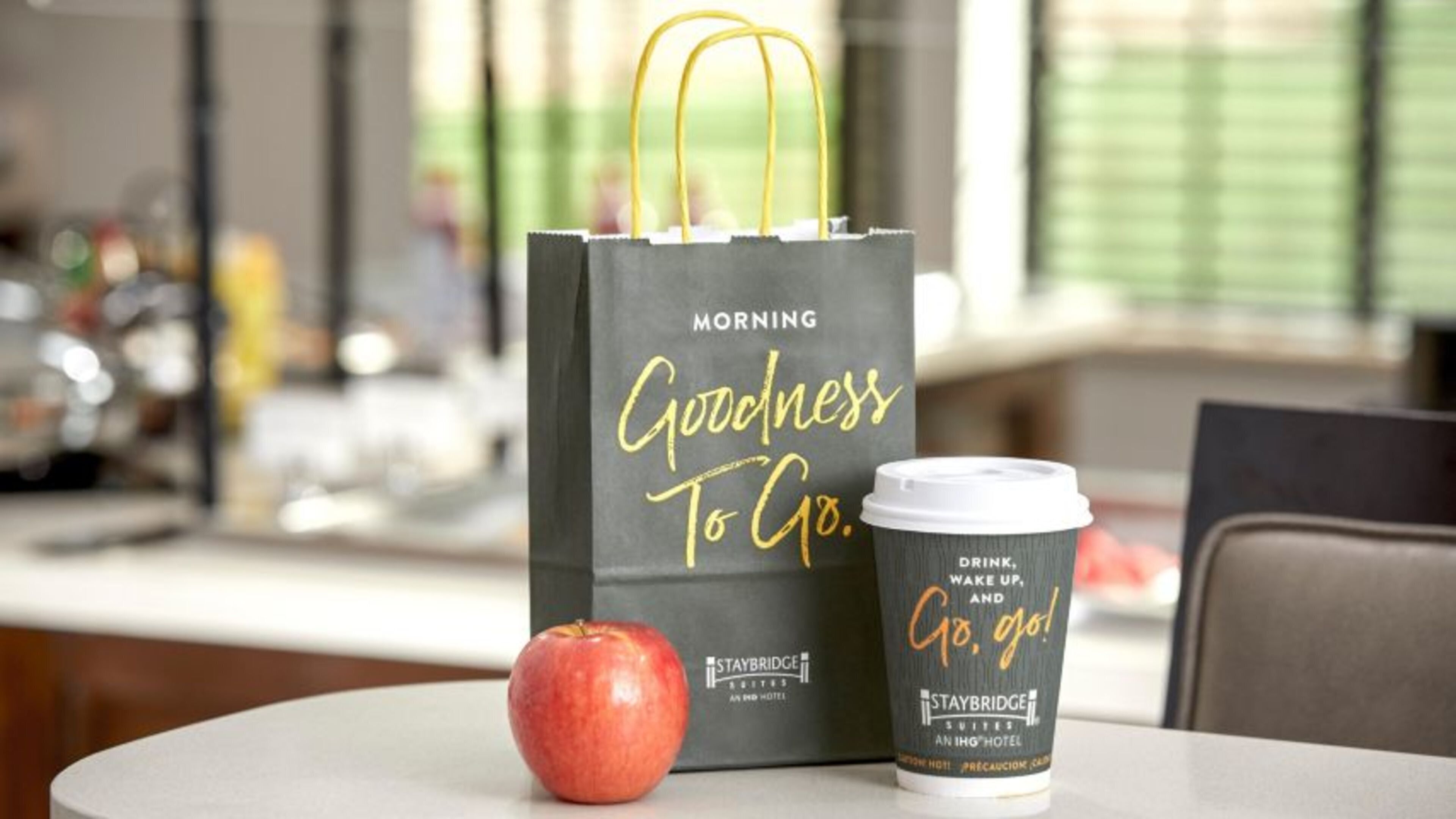 A Staybridge Suites hotel bag with a coffee cup beside it.