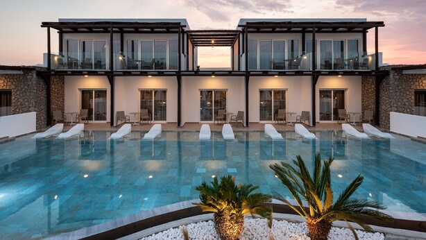 A modern two-story building with a swimming pool, lounge chairs, and a sunset view. - Nama Retreat (Rhodes)